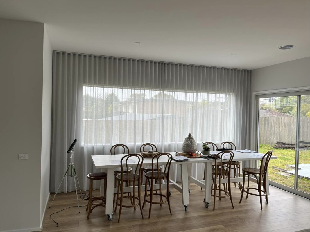 Grey S-Fold sheer curtains drawn across a wide dining room window