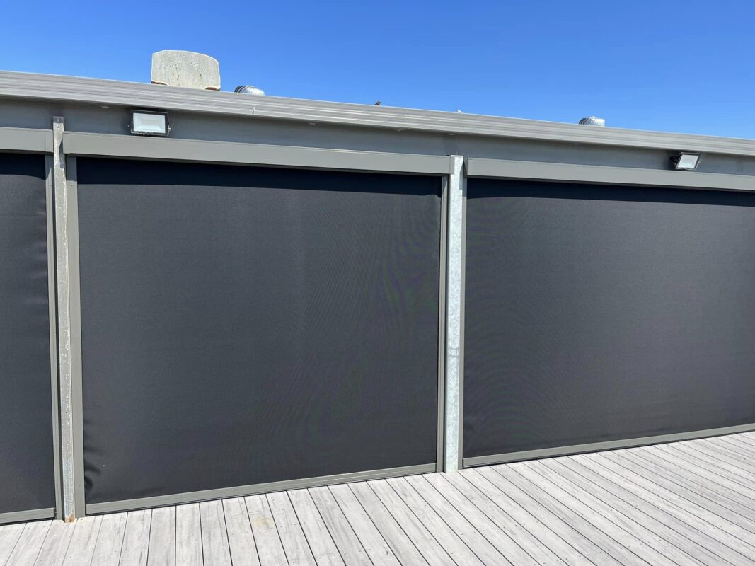Charcoal Zipscreen outdoor blinds held taut in their side tracks against a clear sky