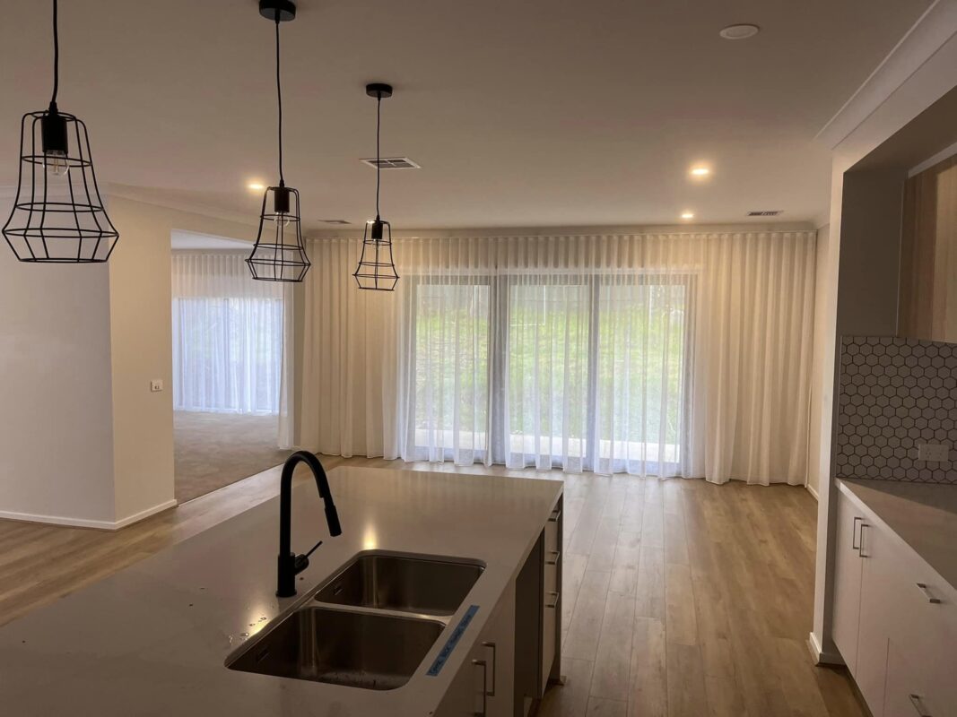 White S-Fold sheer curtains across sliding doors in an open-plan kitchen and living area