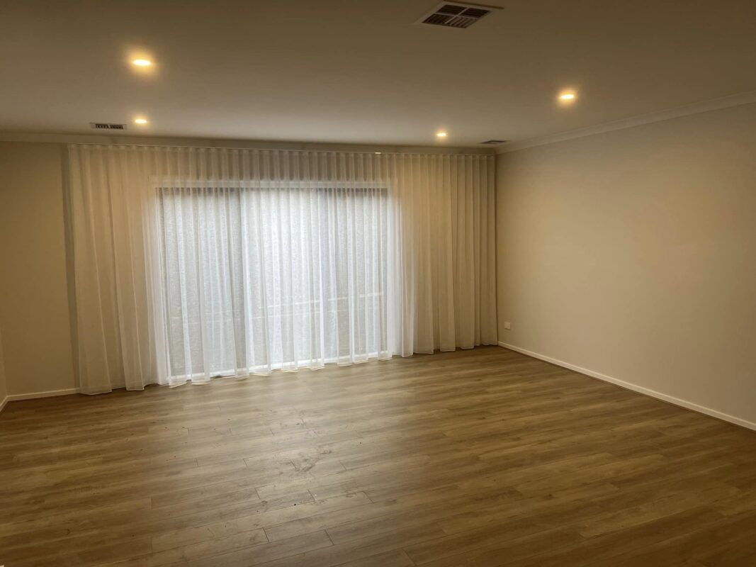White S-Fold sheer curtains framing a sliding door in a living room with timber flooring