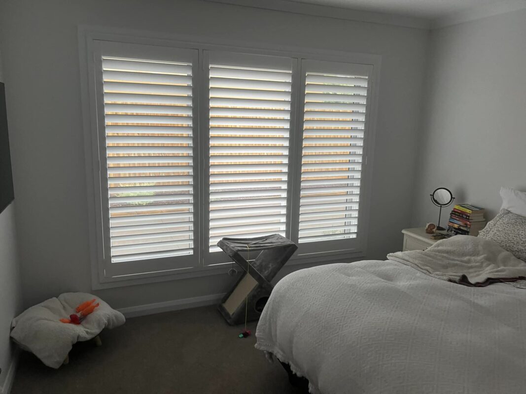 White plantation shutters fitted to a three-panel bedroom window