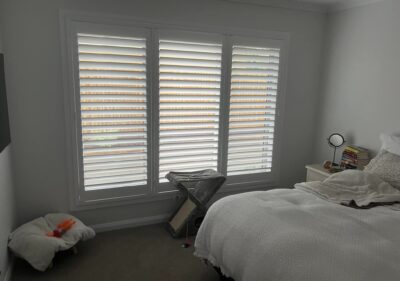 White plantation shutters fitted to a three-panel bedroom window