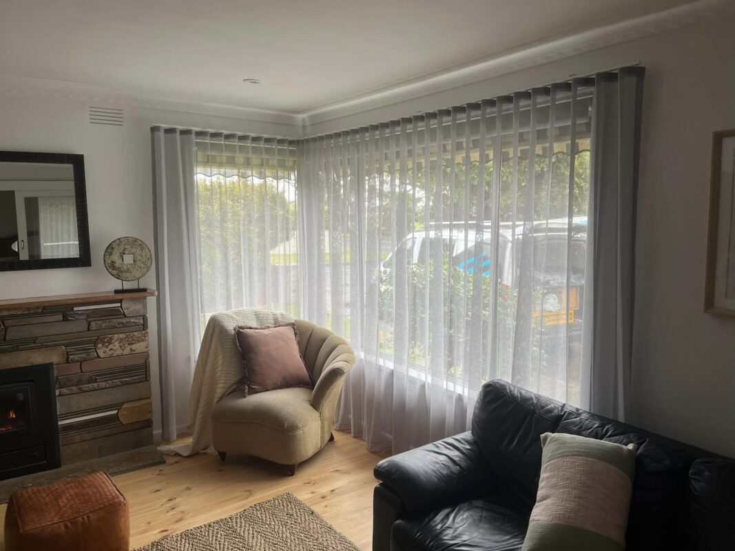 Sheer curtains layered across a corner window in an older lounge room